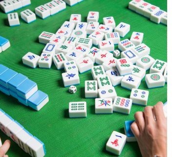 Mahjong tiles, a green table and a human hand.