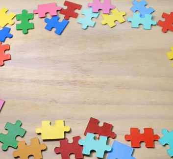 Wooden background with colorful puzzles along top and bottom edges