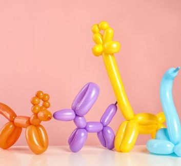 Pink background with orange, purple, and blue balloon animals in foreground.