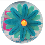 Blue felt flower with yellow light up nodule in the middle. Graph paper background.